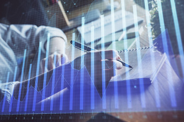 Financial forex charts displayed on woman's hand taking notes background. Concept of research. Double exposure