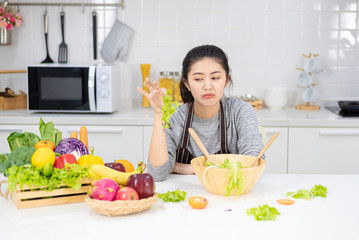 Young Asian girl with boring face due to she needs to loss her weight by eating green salad and fruit. She dislike vegetable so much.copy space, food ideas for weight loss