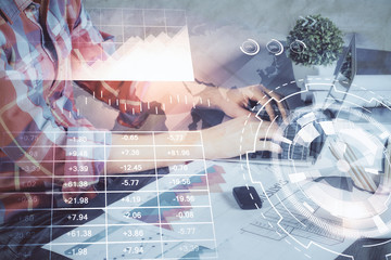 Double exposure of stock graph with businessman typing on computer in office on background. Concept of hard work.