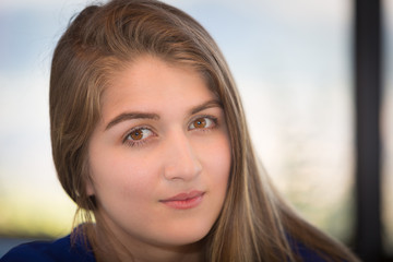 Fototapeta premium Portrait of a young lady. She is latin in her twenties with long brown smooth hair and light brown eyes. She is looking at the camera. She is serious.