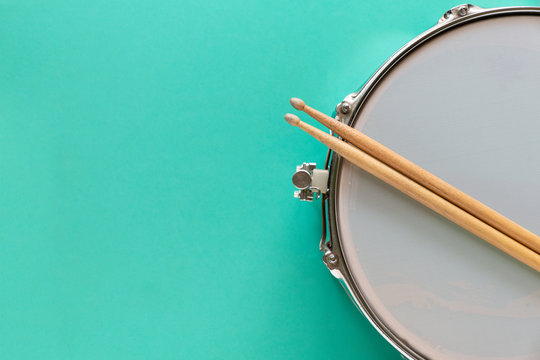 Drum and drum stick on green table background, top view, music concept