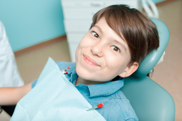 Little boy in dental chair. Smiling and satisfied patient at dentist's office after treatment. Healthy teeth, dental care concept.