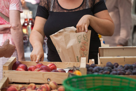 Une vendeuse tient un sac en papier et d&eacute;signe du doigt des p&ecirc;ches