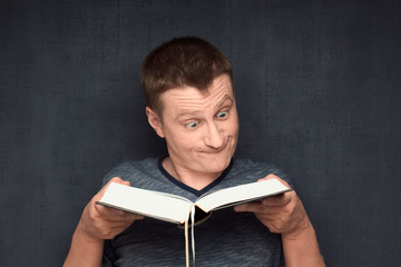 Portrait of funny and perplexed man reading big book