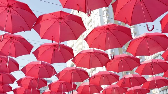 red umbrellas on a blue sky and white building background. Street decorated with red umbrellas