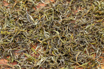 Premium Dry green tea leaves spread curing in bamboo basket tray after harvest