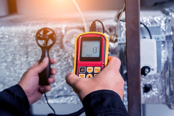 Technician use hand-held anemometer measuring air flowing measurement, wind speed and pressure.