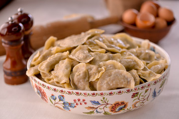 ready-made dumplings Ukrainian national dish in a painted dish on a board with ingredients of eggs and flour