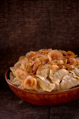 dumplings in a large clay dish on a dark background