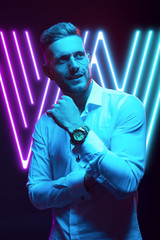 Young handsome model posing in a studio in a trendy neon light. Fashionable man in a stylish suit. Vibrant color. Bright colorful light effects. Disco style. Overlay. Gel filter. Supersaturated