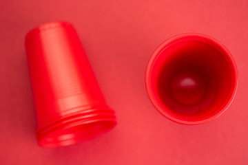 Red plastic glasses on red background, top view