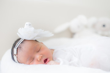 adorable infant girl in white pajama sleeping on white cloth mattress. newborn baby having day nap in parents' bed. childhood dreams. concept of health and children. .