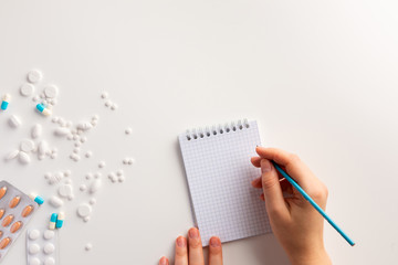 Female hand writing in a notepad. Medical concept. Flat lay.