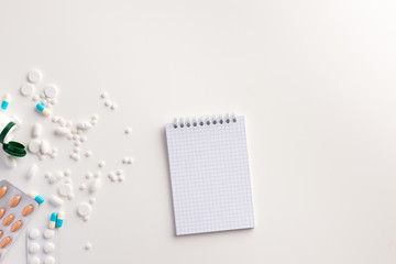 Medicaments and notepad on white background. Medical concept. Flat lay.