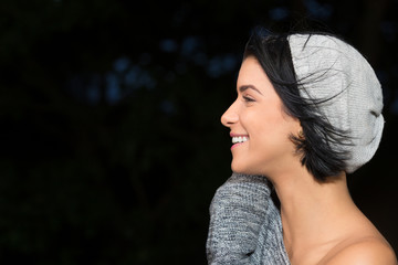 Closeup of a young brunette woman face in profile. She is smiling.