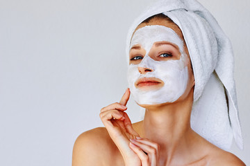 Beautiful woman applying facial mask on her face. Skin care and treatment, spa, natural beauty and...