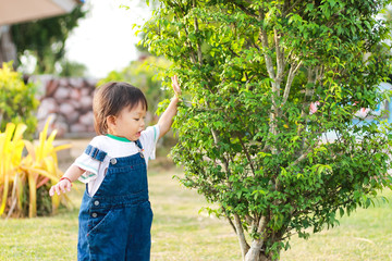 Development of baby aged of 1 years and 4 months olds. Happy Asian child girl walking and relaxing at the garden park.