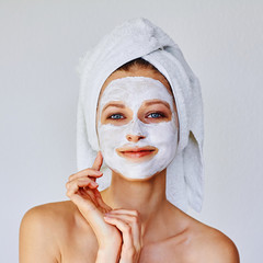 Beautiful woman applying facial mask on her face. Skin care and treatment, spa, natural beauty and...