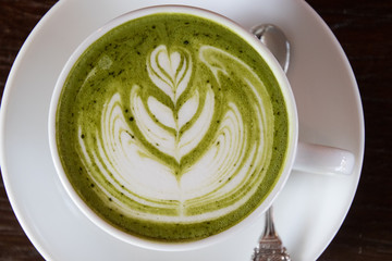 Coffee cup with Green Matcha latte art foam on wood table in coffee shop with copy space.Coffee is one of the most popular beverages.Improve Energy Levels and Burn Fat