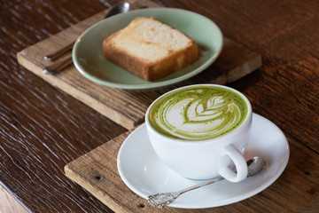 Coffee cup with Green Matcha latte art foam on wood table in coffee shop with copy space.Coffee is one of the most popular beverages.Improve Energy Levels and Burn Fat