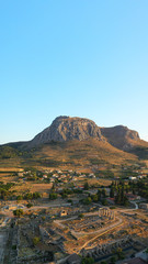 Aerial drone photo of iconic archaeological site of Ancient Corinth featuring temple of Apollo built in the slopes of Acrocorinth, Peloponnese, Greece