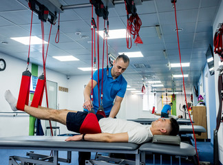 Physiotherapy. Suspension training therapy. Young man doing fitness traction therapy with...