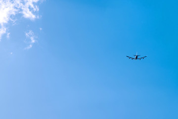 the silhouette of a flying plane in the blue sky and clouds on the background