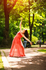 Joyful young woman enjoys dancing in green city park on nature among the trees, concept of freedom and carelessness