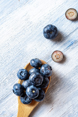 Top view on blueberry in a wooden spoon on blue rustic background. Food concept of natural fruit. Half of blueberry flat lay. Creative layout. Vertical. copy space
