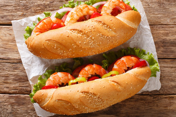 Fresh Sandwich with king prawns, vegetables close-up on parchment. Horizontal top view