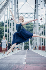 Fototapeta na wymiar Young ballerina dancing in city streets, feeling breath of big city life and freedom 