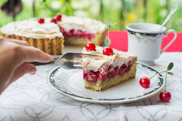 Tart with cherry and meringue. A slice of cherry pie on a plate on the outdoor terrace.