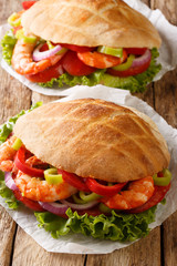 Pita with shrimps, tomatoes, peppers, onions and fresh lettuce close-up on parchment. vertical
