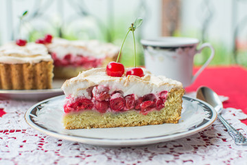 Tart with cherry and meringue. A slice of cherry pie on a plate on the outdoor terrace.