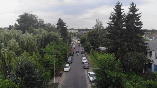 Fly close over a wide road in the village. Flying over the forest and the road. Drone view. Harvest, agriculture concept.