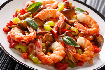 Fried king prawns with mushrooms and vegetables close-up on a plate. horizontal