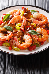 Delicious king prawns with mushrooms and vegetables close-up on a plate. vertical