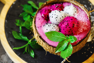 Obraz na płótnie Canvas Close up of dragon fruit smoothie. Fresh red pitaya smoothie in coconut shell cup