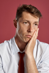 Obraz premium Portrait of a young brunet man posing in a studio against a red background.