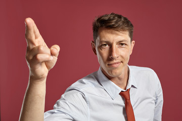 Portrait of a young brunet man posing in a studio against a red background.