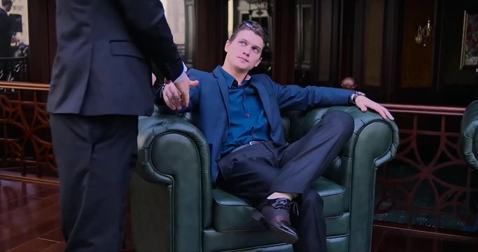 The young blue-eyed businessman waited for a business partner, shook his hand, offered to sit down. Job interview, smart office, blue suit, serious, punctual