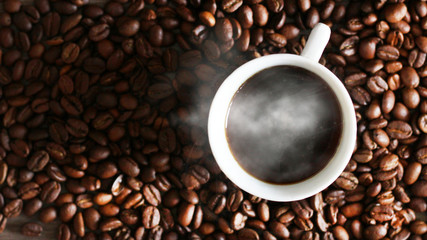 Black coffee in white cup and coffee beans, top view