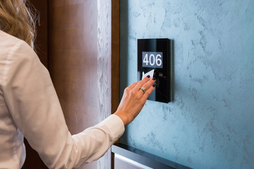 Hand on electronic hotel room access panel with room number