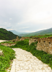 Stone path in the ancient settlement of Hoi against the backdrop of the picturesque mountains of the Greater Caucasus. Masonry without mortar