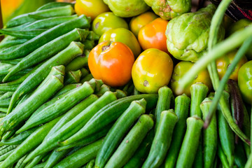 Closeup of vegetable okra (AKA ladies' fingers or ochro), ripe tomatoes and chayote or sayote. Selective focus. 