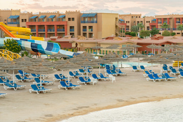 Umbrellas and chaise lounges on the beach. Scenic view of private sandy beach with sun beds from the sea