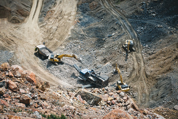 Excavator loading dumper truck on mining site stock photo
