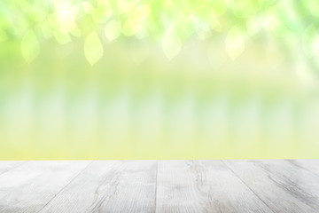 Naklejka na ściany i meble Empty table top summer background. Empty rustic wooden bright table top in front of a beautiful abstract light green spring background. Template for your product display montage.
