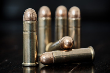 Brass handgun ammunition against a wooden backdrop