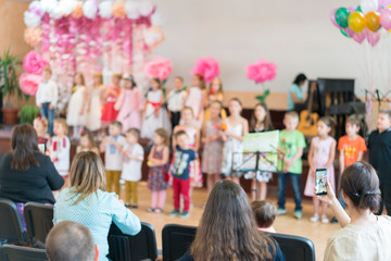 Children's party in primary school. Young children on stage in kindergarten appear in front...